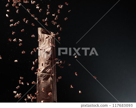 Large piece of dark chocolate and falling chocolate crumbs. Large piece of dark chocolate and falling chocolate crumbs. 117683093