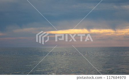 Seascape. Waves and surf. Sunset and dawn at sea. Calm on the ocean. Beautiful sky and clouds illuminated by the sun. Natural background. Summer time. 117684970