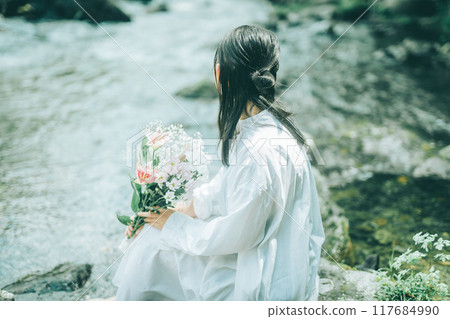 The back view of a woman in a white dress swimming in a river in summer The back view of a woman in a white dress swimming in a river in summer 117684990