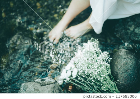 夏季河中穿著白色連身裙的女人的腳和一束鮮花 117685006