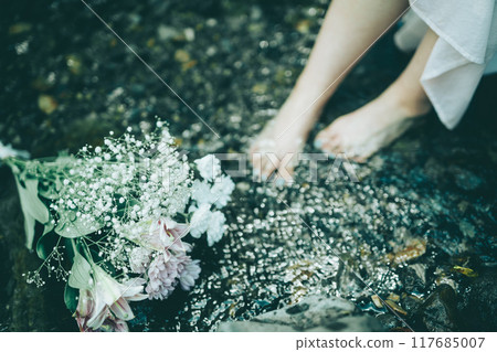 夏季河中穿著白色連身裙的女人的腳和一束鮮花 117685007