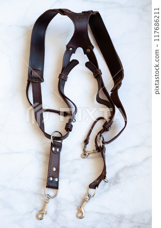 Leather strap for a photographer - a shoulder strap for two cameras. Top view with copy space. Leather strap for a photographer - a shoulder strap for two cameras. Top view with copy space. 117686211