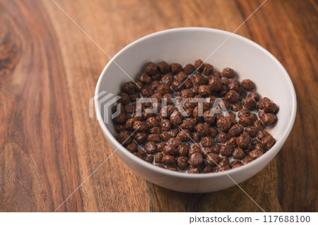chocolate cereal breakfast in white bowl on wood table 117688100