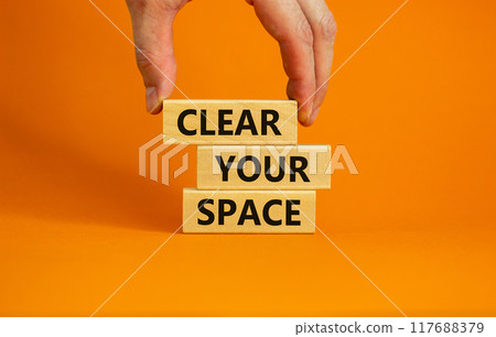 Clear your space symbol. Wooden blocks with words 'Clear your space'. Beautiful orange background, businessman hand. Business, clear your space concept, copy space. 117688379