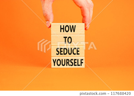 How to seduce yourself symbol. Concept word How to seduce yourself on wooden blocks. Businessman hand. Beautiful orange table orange background. Business and how to seduce yourself concept. Copy space 117688420