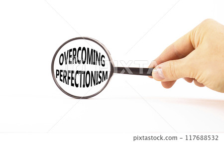 Overcoming perfectionism symbol. Concept words Overcoming perfectionism in magnifying glass. Beautiful white paper background. Businessman hand. Business Overcoming perfectionism concept. Copy space. Overcoming perfectionism symbol. Concept words Overcoming perfectionism in magnifying glass. Beautiful white paper background. Businessman hand. Business Overcoming perfectionism concept. Copy space. 117688532