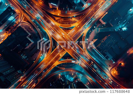Aerial view of a highway intersection at night showing traffic flow on the roads, with a city background. Cars at a big crossroads at night. Urban landscape 117688648