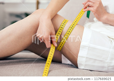 Diet image of a woman measuring her feet 117689025