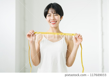 A woman happy to hold a tape measure 117689033