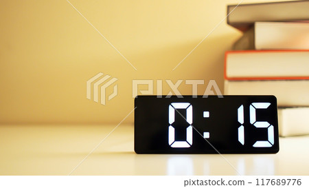 Digital Alarm Clock Displaying 0.15 with Books on a Shelf - Ideal for Time-Related Concepts and Educational Content 117689776