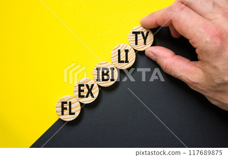 Flexibility symbol. Concept word Flexibility on beautiful wooden circles. Beautiful yellow and black background. Businessman hand. Business flexibility concept. Copy space. 117689875