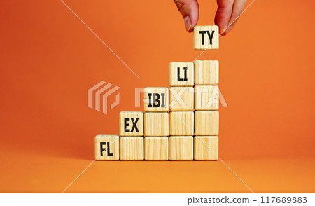 Flexibility symbol. Concept word Flexibility on beautiful wooden cubes. Beautiful orange background. Businessman hand. Business flexibility concept. Copy space. 117689883
