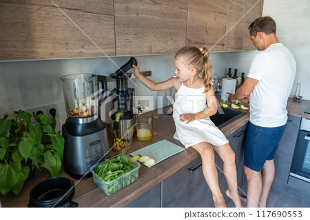 Family with a young father and his little daughter preparing a healthy juice or smoothie with fresh fruits in home kitchen 117690553