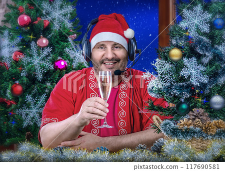 Virtual Christmas Cheer with Santa-Clad Man in Headset Toasting Wine, Surrounded by Christmas Trees and Festive Holiday Ornaments. 117690581
