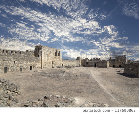 Ruins of Azraq Castle (Qasr al-Azraq) is a crusader castle (300AD),  central-eastern Jordan, 100 km east of Amman, Jordan. Against the background of a beautiful sky with clouds 117690862