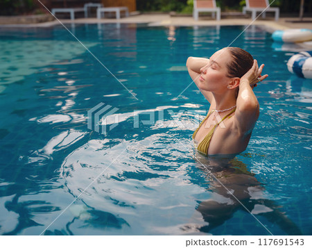 Vacation lifestyle scene of young woman sitting in swimming pool Vacation lifestyle scene of young woman sitting in swimming pool 117691543