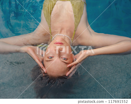 Vacation lifestyle scene of young woman sitting in swimming pool 117691552
