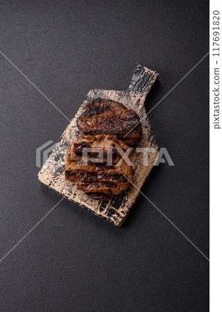 Fresh juicy delicious beef steak on a dark background Fresh juicy delicious beef steak on a dark background 117691820
