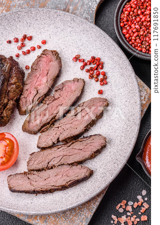 Fresh juicy delicious beef steak on a dark background Fresh juicy delicious beef steak on a dark background 117691850