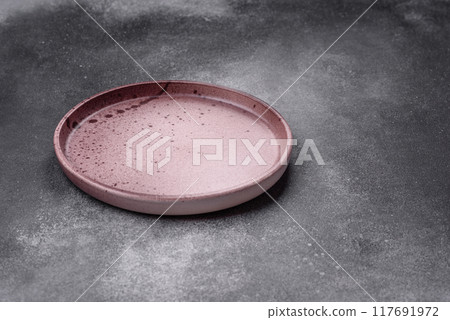 Empty ceramic plate on a dark textured background Empty ceramic plate on a dark textured background 117691972