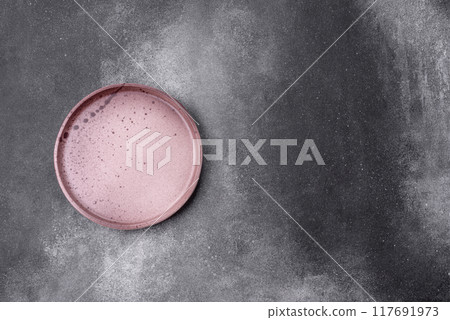 Empty ceramic plate on a dark textured background Empty ceramic plate on a dark textured background 117691973