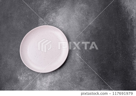 Empty ceramic plate on a dark textured background Empty ceramic plate on a dark textured background 117691979