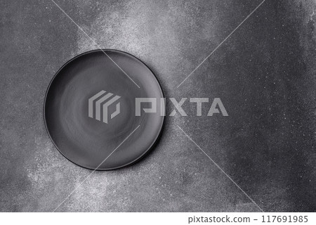 Empty ceramic plate on a dark textured background 117691985