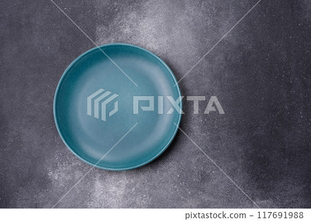 Empty ceramic plate on a dark textured background Empty ceramic plate on a dark textured background 117691988