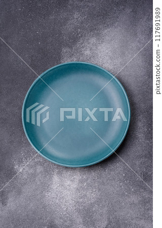 Empty ceramic plate on a dark textured background 117691989