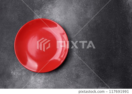 Empty ceramic plate on a dark textured background Empty ceramic plate on a dark textured background 117691991