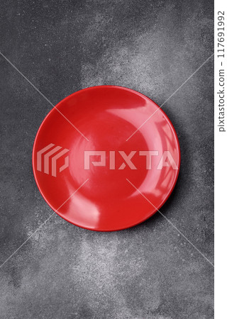 Empty ceramic plate on a dark textured background Empty ceramic plate on a dark textured background 117691992