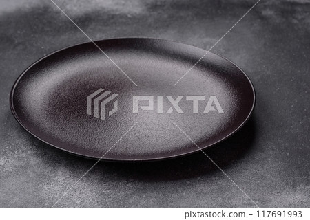 Empty ceramic plate on a dark textured background 117691993