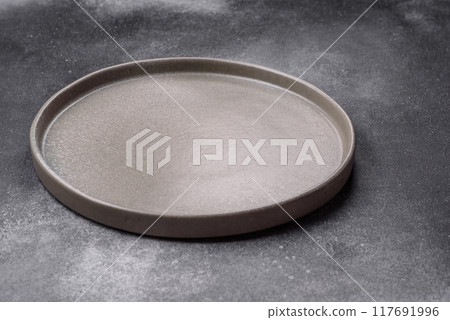 Empty ceramic plate on a dark textured background 117691996