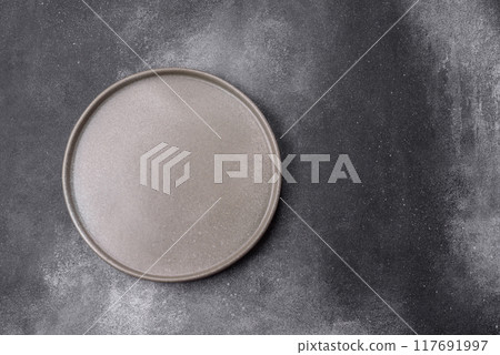 Empty ceramic plate on a dark textured background 117691997