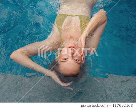 Vacation lifestyle scene of young woman sitting in swimming pool 117692168