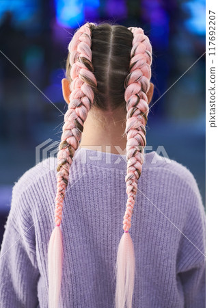 A child with pigtails made of pink kanekalon. He stands with his back to the camera, showing his braided hair. There is a place to copy. High quality photo A child with pigtails made of pink kanekalon. He stands with his back to the camera, showing his braided hair. There is a place to copy. High quality photo 117692207
