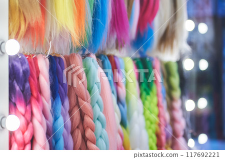 Artificial material for braiding pigtails. A colored kanekalon hangs on the wall, different materials for Afro-pigtails with space for copying. High quality photo Artificial material for braiding pigtails. A colored kanekalon hangs on the wall, different materials for Afro-pigtails with space for copying. High quality photo 117692221