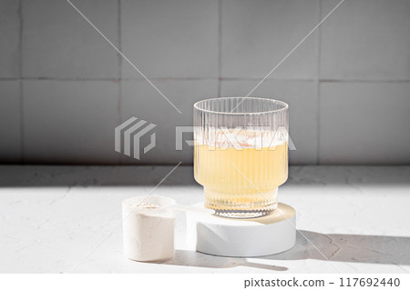 Collagen protein powder in a scoop. Glass of collagen beauty drink. Food supplement. Collagen protein powder in a scoop. Glass of collagen beauty drink. Food supplement. 117692440