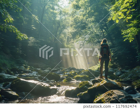 woman standing on rocks in river, surrounded by mountains forest. Idea of adventure and wanderlust 117692474