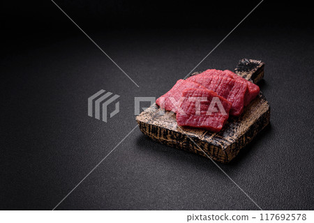 Juicy fresh raw beef meat with salt, spices and herbs Juicy fresh raw beef meat with salt, spices and herbs 117692578