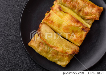 Homemade fried pancakes with filling on a ceramic plate 117694839