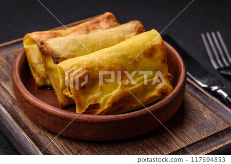 Homemade fried pancakes with filling on a ceramic plate 117694853
