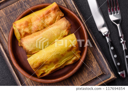 Homemade fried pancakes with filling on a ceramic plate 117694854