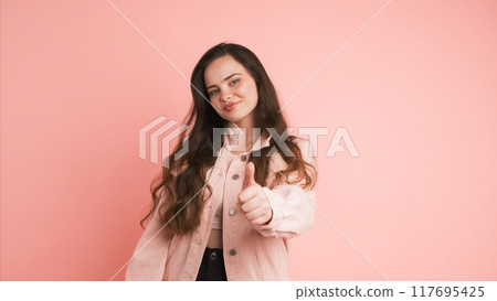 Happy young woman showing thumbs up in pink studio Happy young woman showing thumbs up in pink studio 117695425