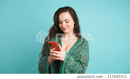 Happy young woman using smartphone in blue studio Happy young woman using smartphone in blue studio 117695431