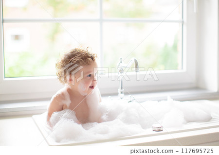 Baby taking bath in kitchen sink Baby taking bath in kitchen sink 117695725