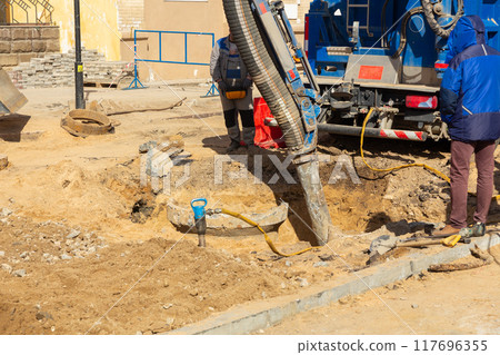 Workers use a suction excavator based on a truck to sample soil in a well for communications 117696355