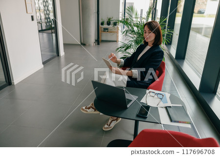 In an office, a businesswoman is working with a laptop and tablet to increase productivity 117696708