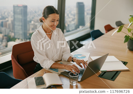 A Professional Woman Engaged in Work Within a Modern Office Setting and Environment 117696726