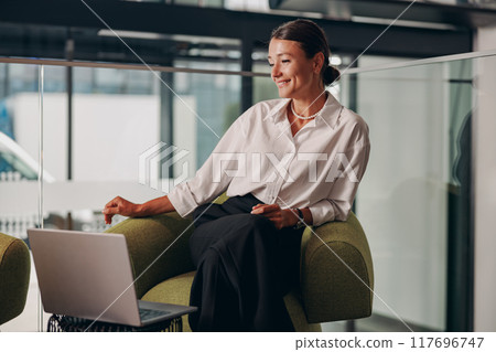 A Professional Woman Actively Engaged in Her Work within a Modern Office Environment 117696747